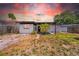 The charming exterior of the home is enhanced by lovely landscaping and vibrant sunset at 4684 72 N Ave, Pinellas Park, FL 33781