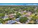 An aerial view of a residential area with lush greenery, backyard pools, and a distant cityscape under a blue sky at 4915 Chariton Ave, Tampa, FL 33603