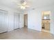 White bedroom featuring a ceiling fan, terrazzo floors, and an ensuite bathroom at 4915 Chariton Ave, Tampa, FL 33603