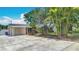 Charming single-story home with a covered parking area, front garden featuring lush, mature palm trees, and a well-maintained lawn at 4915 Chariton Ave, Tampa, FL 33603