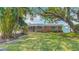 A beautifully maintained brick home with green shutters, surrounded by mature landscaping and a well-manicured lawn at 4915 Chariton Ave, Tampa, FL 33603