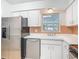 Bright kitchen featuring white cabinets, stainless steel refrigerator and dishwasher with a view to the backyard at 4915 Chariton Ave, Tampa, FL 33603