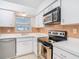 Well-lit kitchen featuring white cabinets, stainless steel appliances, and neutral tiled backsplash at 4915 Chariton Ave, Tampa, FL 33603