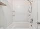 White tiled bathtub with shower head and built-in shelves at 5115 Stonehaven Ct, Tampa, FL 33624
