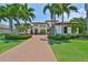 Elegant two-story home featuring a well-manicured lawn, mature palm trees, and a brick-paved driveway at 5417 Tybee Island Dr, Apollo Beach, FL 33572