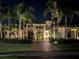 Beautifully lit front of home with a brick-paved driveway lined with palm trees and lush landscaping at 5417 Tybee Island Dr, Apollo Beach, FL 33572