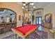 Well-lit game room featuring a classic pool table under an ornate chandelier, complemented by rich architectural details at 5417 Tybee Island Dr, Apollo Beach, FL 33572