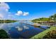 Scenic lake view featuring a dock, boat and kayak storage framed by lush greenery and a calm sky reflection at 5417 Tybee Island Dr, Apollo Beach, FL 33572