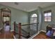 Upstairs landing with beautiful hardwood floors, wooden railings, and natural lighting from the arched window at 5417 Tybee Island Dr, Apollo Beach, FL 33572