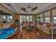A living room with hardwood floors, a ceiling fan, tray ceiling, large windows, and comfortable seating arrangement at 5417 Tybee Island Dr, Apollo Beach, FL 33572