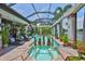 The screened in pool area includes a spa with a connecting swimming pool and many decorative plants and lawn chairs at 5417 Tybee Island Dr, Apollo Beach, FL 33572