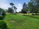 Expansive backyard featuring a lush lawn, mature trees, and access to a golf course at 611 Tremont Greens Ln, Sun City Center, FL 33573
