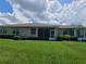The home's backyard shows manicured shrubs, healthy green grass, and a screened in patio at 611 Tremont Greens Ln, Sun City Center, FL 33573