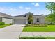 Charming single-story home with well-manicured lawn, gray exterior and two-car garage under a sunny sky at 6123 Golden Nettle Dr, Apollo Beach, FL 33572