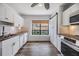 Bright kitchen featuring white cabinets, stainless appliances, wood floors, and a garden view window at 660 Channing Dr, Palm Harbor, FL 34684
