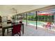 Screened patio with dining table and view of the pool with red umbrellas at 7700 Willow Brook Ct, Hudson, FL 34667
