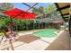 Screened-in pool area with red umbrellas and patio furniture at 7700 Willow Brook Ct, Hudson, FL 34667