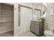 Well-lit bathroom featuring a shower/tub combo, a vanity, a round mirror, and an open shelving unit at 909 E 15Th Ave, Tampa, FL 33605