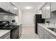 Galley kitchen with modern cabinets, black appliances, and subway tile backsplash at 909 E 15Th Ave, Tampa, FL 33605
