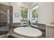 Bathroom with soaking tub, tiled accents and bright windows at 9348 Deer Creek Dr, Tampa, FL 33647