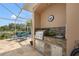 Covered outdoor kitchen featuring stone accents, stainless steel grill, sink and food preparation area, and nearby lounge seating at 9348 Deer Creek Dr, Tampa, FL 33647