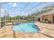 Screened swimming pool and spa with stone patio and view of the backyard at 9348 Deer Creek Dr, Tampa, FL 33647