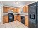 Well-lit kitchen featuring wood cabinets, a black oven range, and a black refrigerator at 10110 Pepperidge Ct, Tampa, FL 33615