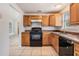 Traditional kitchen with wood cabinets, black appliances, and tile flooring at 10110 Pepperidge Ct, Tampa, FL 33615