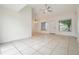Open-concept living room with neutral tile flooring, vaulted ceiling, and bright natural light at 10110 Pepperidge Ct, Tampa, FL 33615
