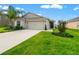 Charming single-story home with a well-manicured lawn, palm tree and a two-car garage on a sunny day at 10512 Fuzzy Cattail St, Riverview, FL 33578