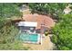 Aerial view of the property showcasing the pool, roof, and surrounding neighborhood's mature trees at 107 Halton Cir, Seffner, FL 33584
