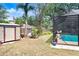 Spacious backyard with a storage shed, lush greenery, and a view of the screened-in pool area at 107 Halton Cir, Seffner, FL 33584