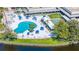 A high angle view of a pool area with a kidney shaped pool, tennis court and lounge chairs at 11224 82Nd Ave # 104, Seminole, FL 33772