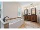 Bright bathroom features a tub, travertine floors, and a vanity with double sinks at 118 S Manhattan Ave, Tampa, FL 33609