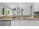 Modern kitchen sink with stone countertops, white cabinetry, stainless steel appliances, and view of living room at 12009 Wandsworth Dr, Tampa, FL 33626