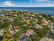 Wide aerial shot showcases the property's location, surrounded by trees and overlooking a stunning ocean view at 122 Miramar Ne Blvd, St Petersburg, FL 33704