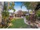 Lush backyard with a stone walkway, green lawn, mature trees, and flowering bushes at 122 Miramar Ne Blvd, St Petersburg, FL 33704