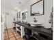 Bright bathroom featuring double sinks, black countertops, terracotta tiled floors, and a decorative mirror at 122 Miramar Ne Blvd, St Petersburg, FL 33704