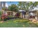Charming exterior features lush landscaping, a cozy bench, and a pergola-covered patio, creating an inviting outdoor space at 122 Miramar Ne Blvd, St Petersburg, FL 33704