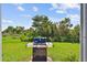 View of the backyard with a well-kept lawn, lush greenery, and an outdoor grill perfect for barbecues at 12716 Evington Point Dr, Riverview, FL 33579