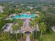 Aerial view of a tropical-style pool area with many palms trees and a clubhouse with solar panels at 12716 Evington Point Dr, Riverview, FL 33579
