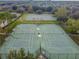 Aerial view of tennis and basketball courts surrounded by green spaces and trees, perfect for community recreation at 12716 Evington Point Dr, Riverview, FL 33579