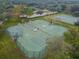 Aerial view of a fenced tennis court complex surrounded by lush greenery and mature trees at 12716 Evington Point Dr, Riverview, FL 33579