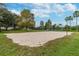 Sandy volleyball court surrounded by grass and trees, with a net ready for a game under a blue sky at 12716 Evington Point Dr, Riverview, FL 33579