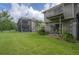 Spacious backyard featuring a screened patio, upper balcony, lush lawn, and a tranquil setting at 14116 Trouville Dr, Tampa, FL 33624