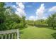 Balcony view showcasing lush greenery, a serene pond, and a clear, partly cloudy sky at 14116 Trouville Dr, Tampa, FL 33624
