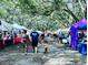 A vibrant outdoor market with many vendors and shoppers enjoying a day outdoors beneath the trees at 14116 Trouville Dr, Tampa, FL 33624