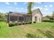Exterior view of a house with a screened-in patio and a lush green lawn at 16104 Bridgedale Dr, Lithia, FL 33547