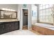 Elegant bathroom features tiled shower and floors, soaking tub, and dark wood vanity at 16104 Bridgedale Dr, Lithia, FL 33547