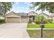 Charming single-story home with a well-manicured lawn, mature trees, and a three-car garage at 16104 Bridgedale Dr, Lithia, FL 33547